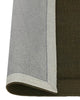Close up of the Cassio Jasper NZ wool floor rug in a deep olive shade with edge rolled to show backing