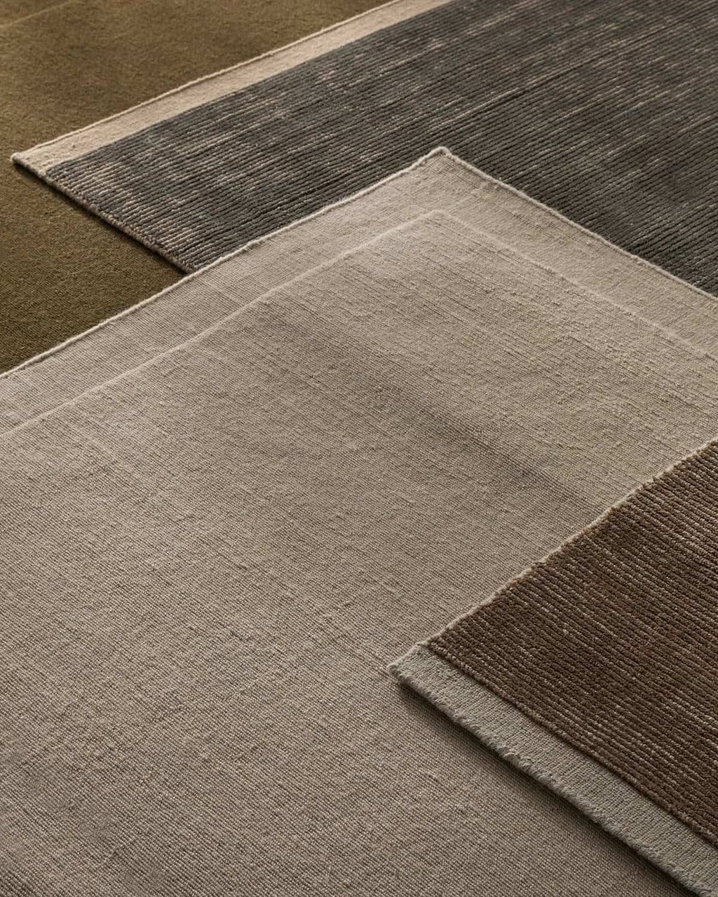 Close-up of three textured rugs with different patterns and colors.
