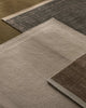 Close-up of three textured rugs with different patterns and colors.
