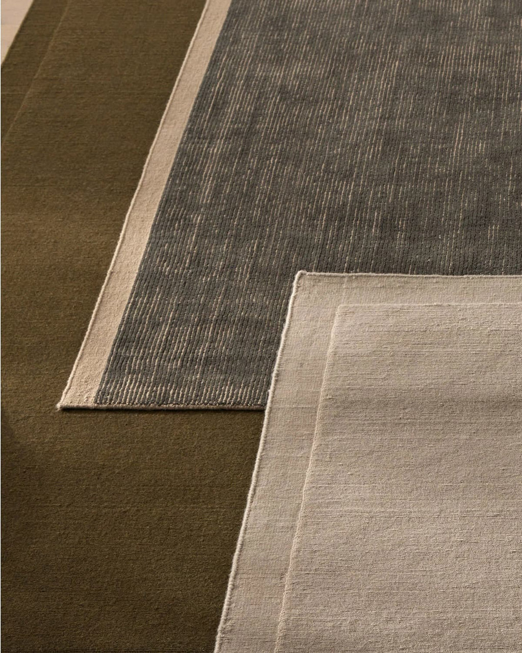 Close-up of three different textured rugs in green, navy, and beige.