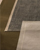 Close-up of three different textured rugs in green, navy, and beige.