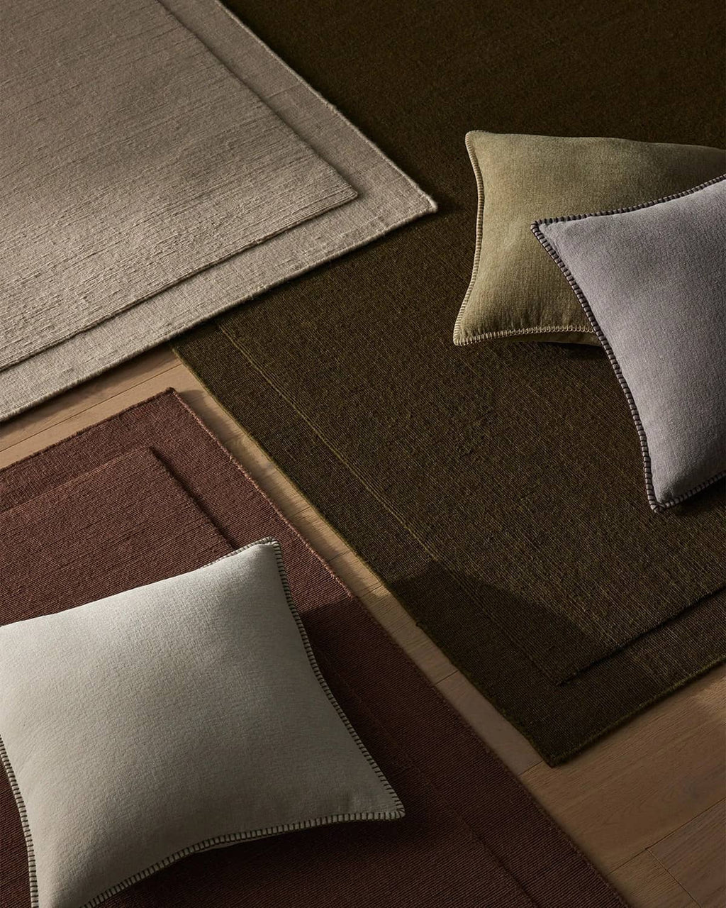 Three NZ wool rugs in beige, chocolate brown and burgundy with a scatter of designer cushions