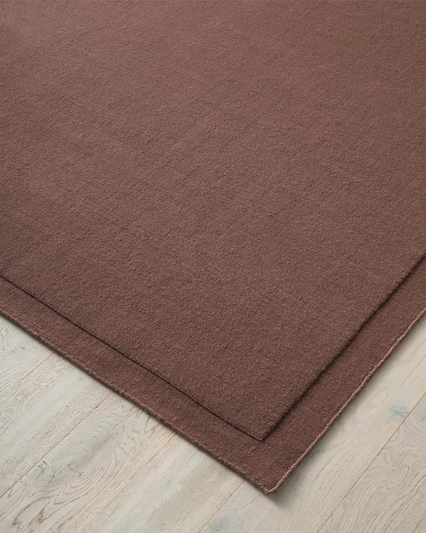 A close up corner view of a burgundy NZ wool rug with frame feature by Weave Home