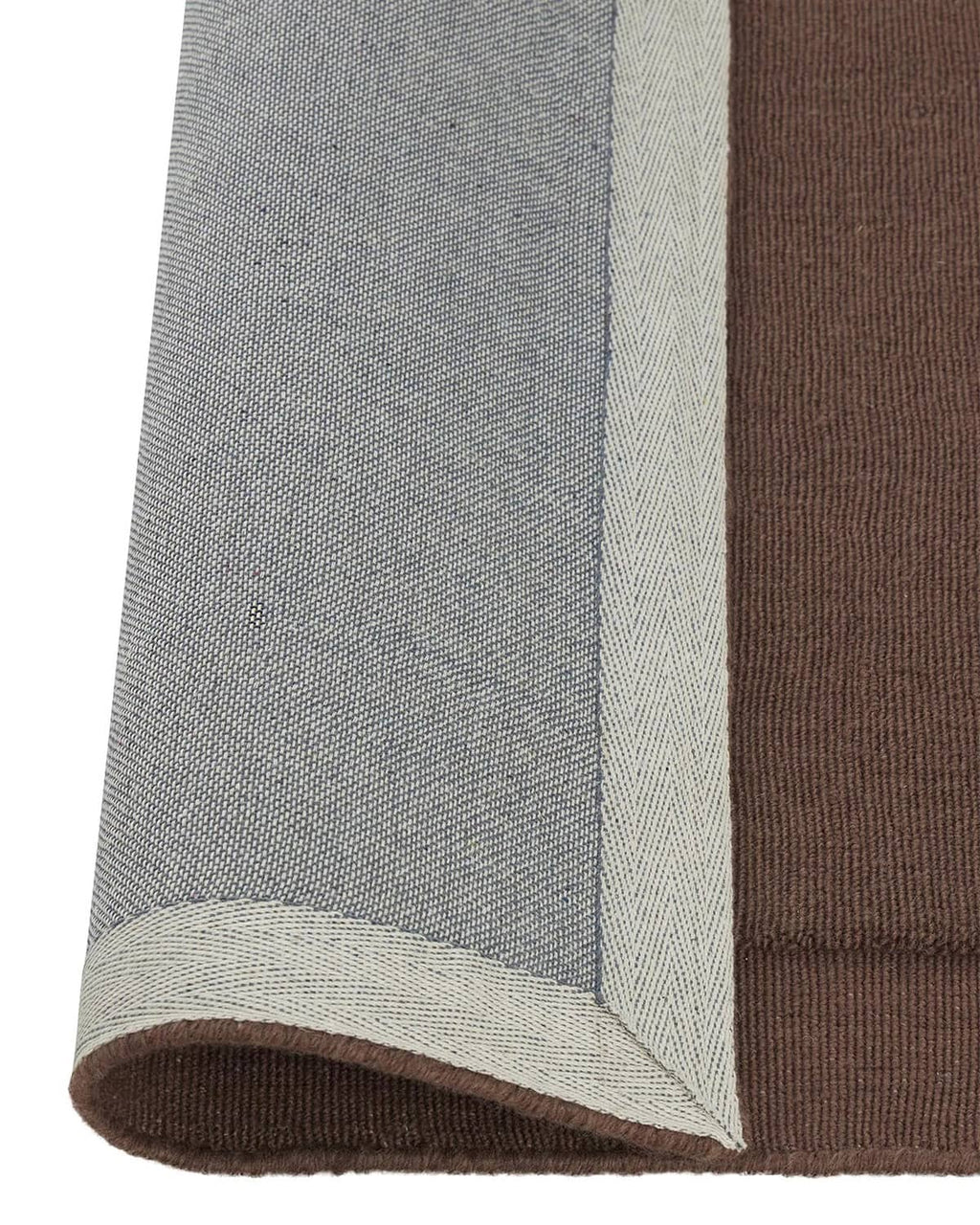 A burgundy NZ wool lrug with frame feature by Weave Home showing the backing rolled up