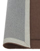 A burgundy NZ wool lrug with frame feature by Weave Home showing the backing rolled up