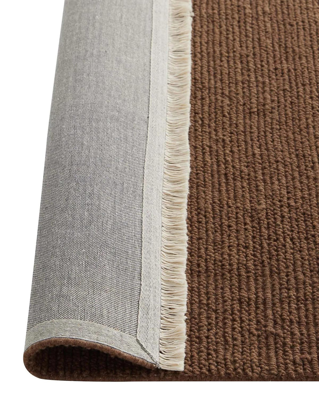 Close-up of a brown rug corner with a white fringe, folded over to view the underside.