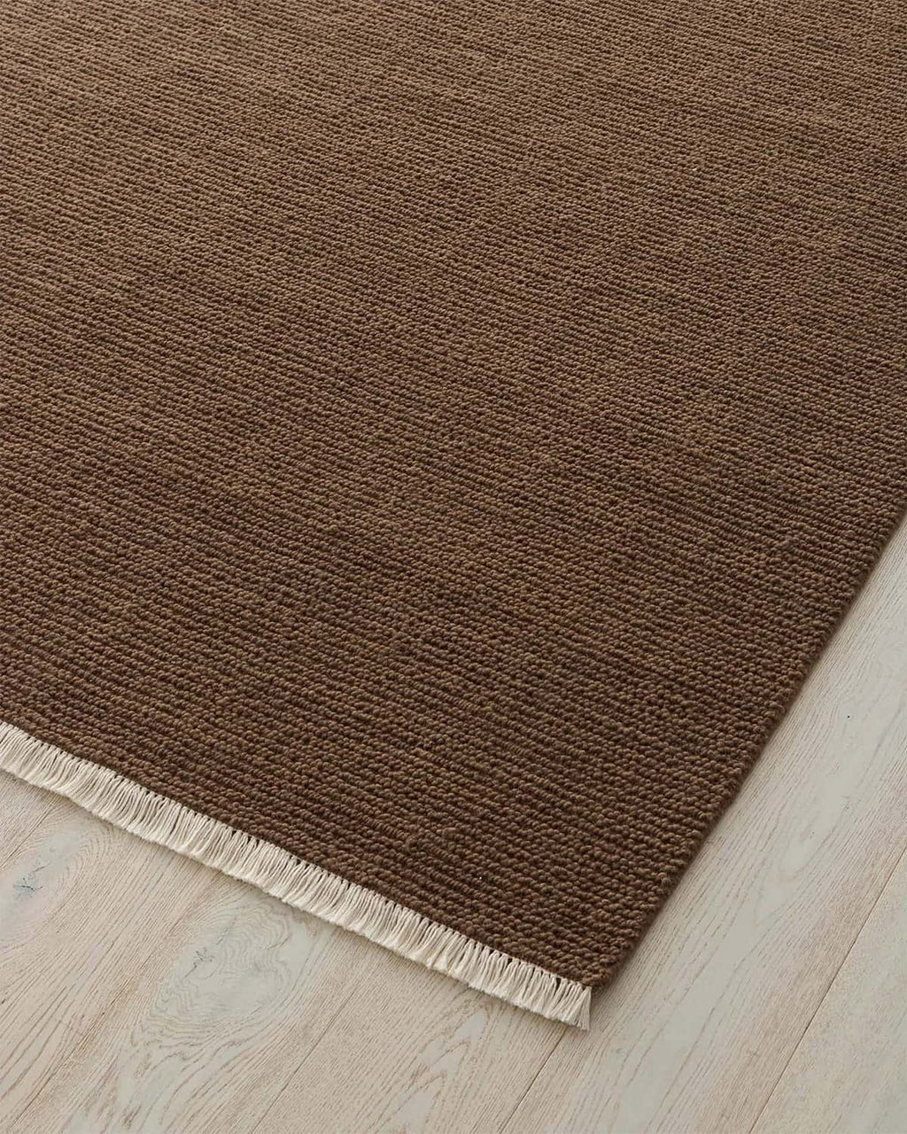 Brown rug with a textured pattern on a light wood floor