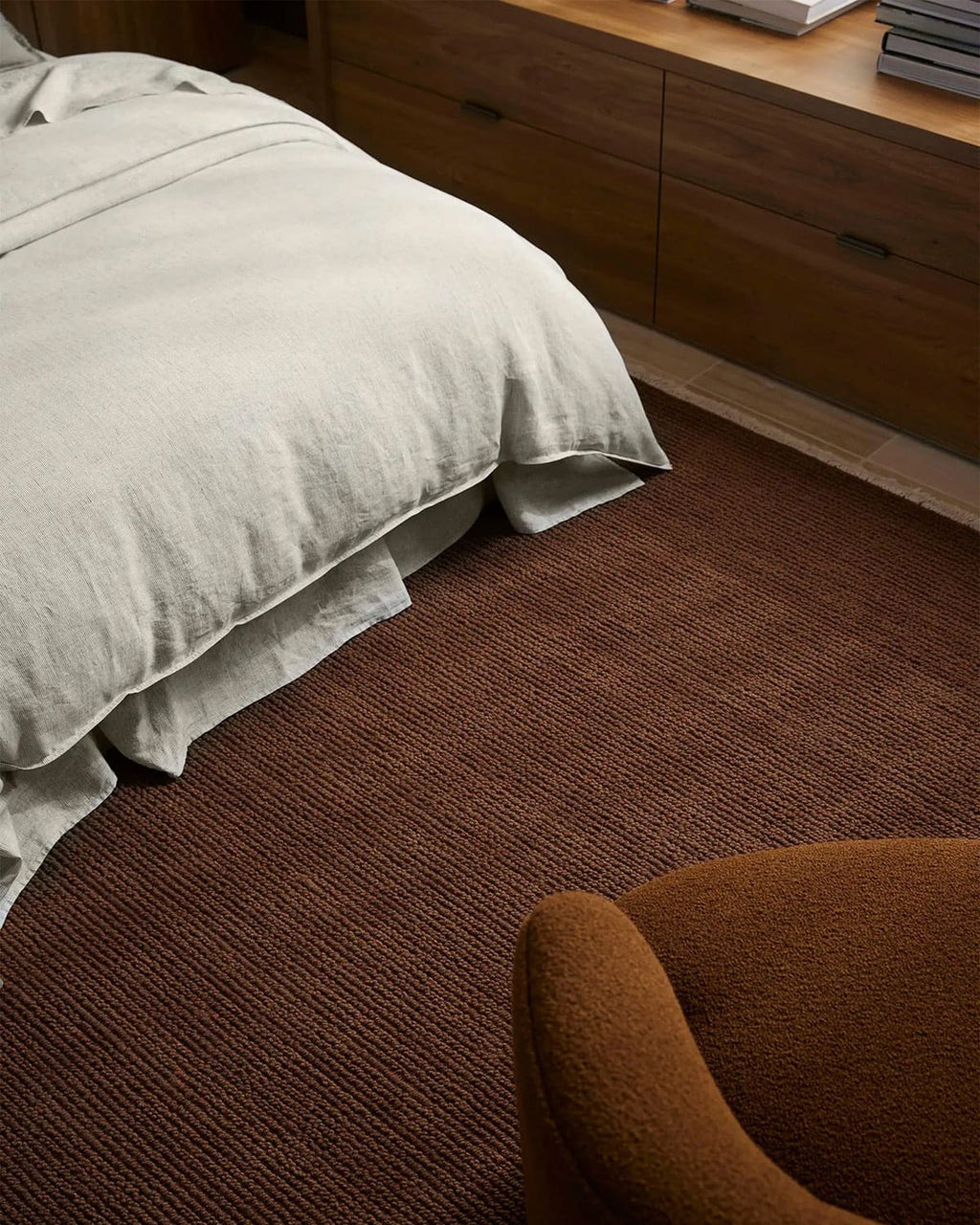 100% wool warm toned textural brown rug in a room with a bed and wooden furniture.