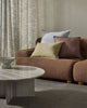 Brown sofa with decorative pillows in a living room setting with a grey textural floor rug. 