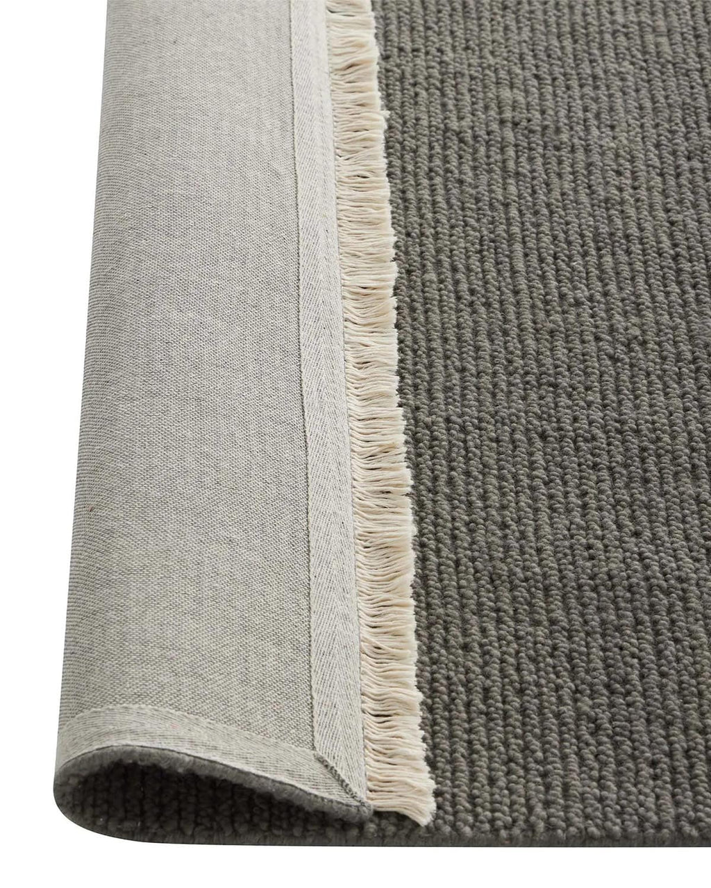 Gray rug with a textured pattern and white fringe on a plain background, the corner flipped to see the underside. 