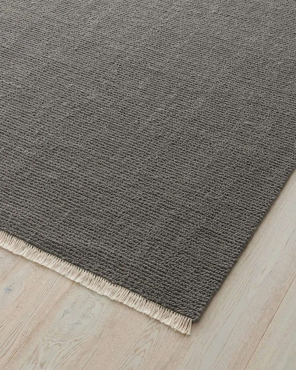 Gray rug with a textured surface on a light wood floor