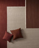 Three textural rugs in warm tones laid atop of each other with two cushions. 