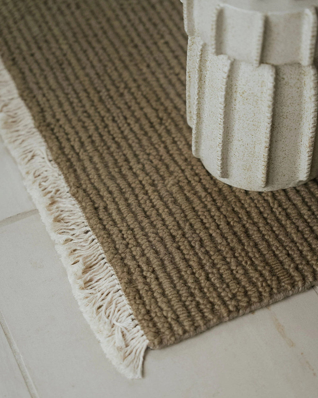 Textured brown rug with white fringe on a light-colored floor