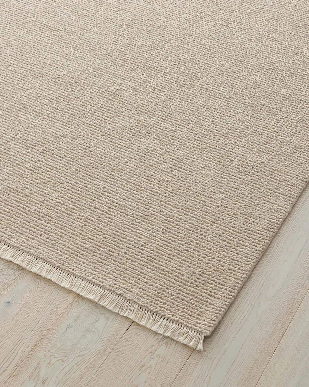 Beige rug with a textured pattern on a wooden floor