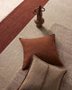 Brown pillow and vase on a number of warm toned floor rugs