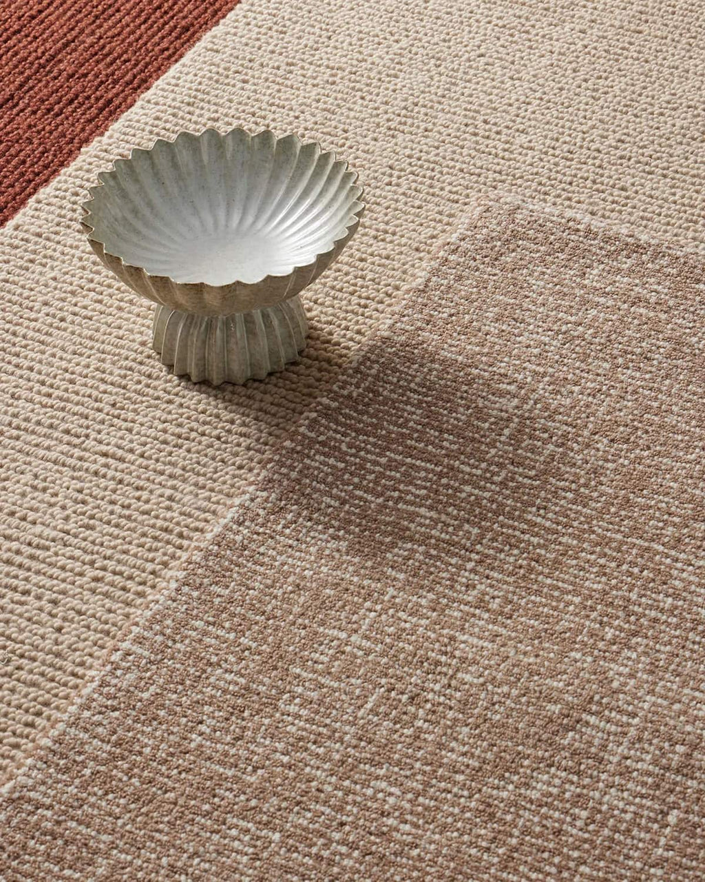 Decorative ceramic bowl on a textured beige floor rug in 100% wool