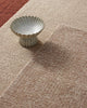Decorative ceramic bowl on a textured beige floor rug in 100% wool