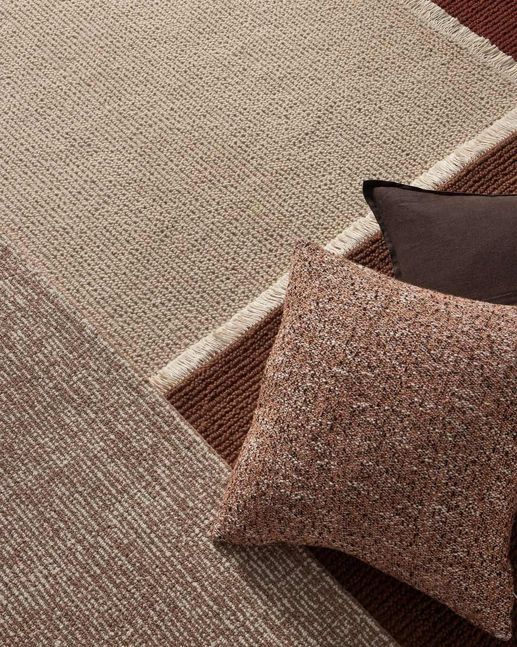 Textured beige floor rug with pillows.