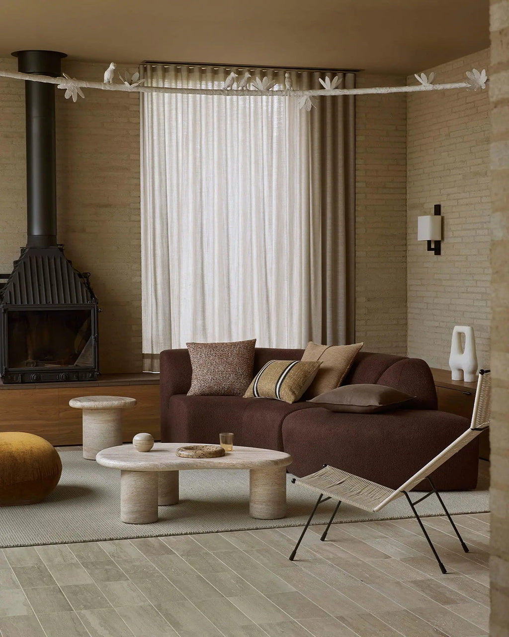 Modern living room with brown sofa, stone coffee table, and decorative elements including a textural beige floor rug.