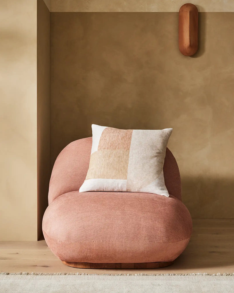 The Weave Home nz Erina cushion featuring on a rounded soft, designer coral-coloured chair