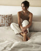 A lady seated on a bed among Weave Home premium  bedding and cushions