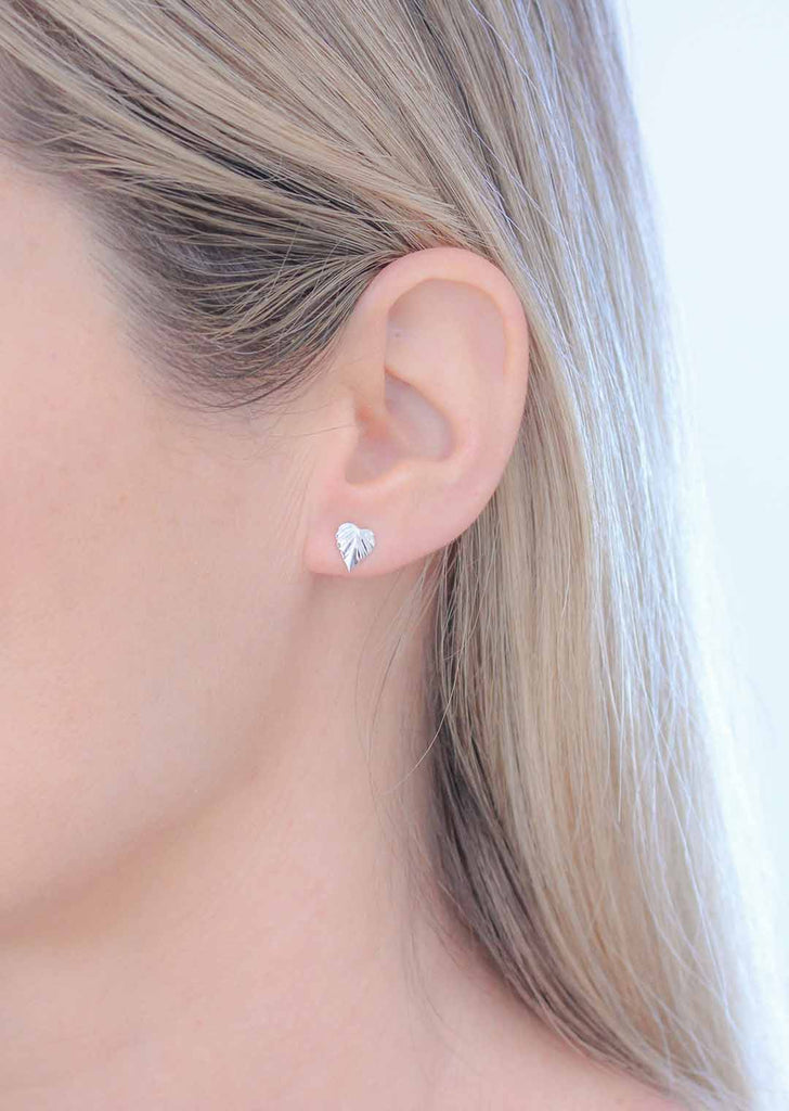 Wild silver stud earrings featuring an NZ Kawakawa leaf design, worn by a model