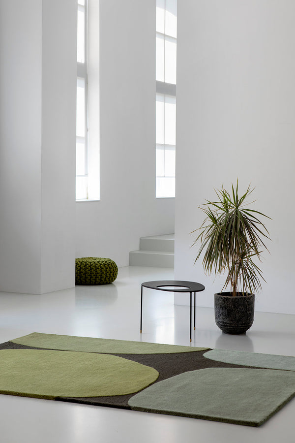 A modern floor rug, featuring varying green tones in a modern design, in a contemporary minimalist living space