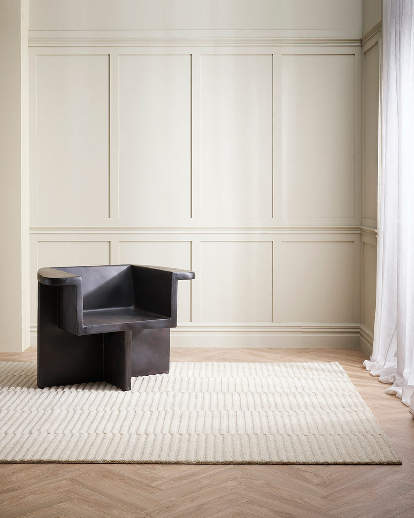 A sitting room in shades of white and cream with a textural linear patterned floor rug in soft cream, 100% wool. By Baya. 