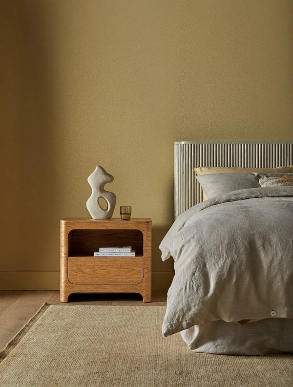 100% wool rug in a warm ochre colour with a contrast frame detail, seen in a  stylish bedroom