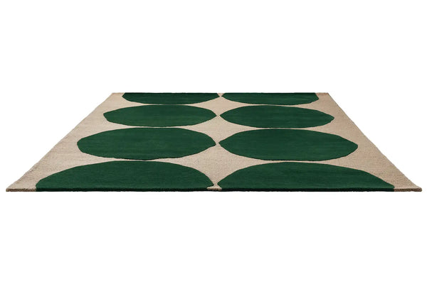 Perspective view of The Marimekko Isot Kivet rug in a rich green and cream