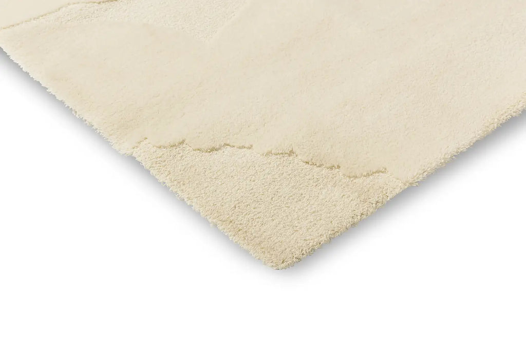 Close up corner view of the The Marimekko Isot Kivet wool floor rug in a calming natural white colour
