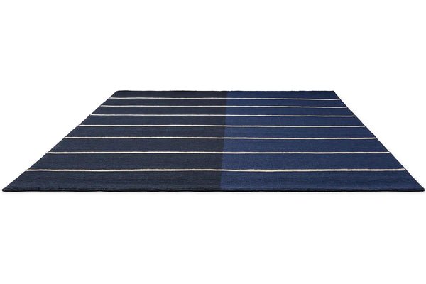Perspective view of the Marimekko Tiibet floor rug, made from recycled PET yarns, in a deep blue colour