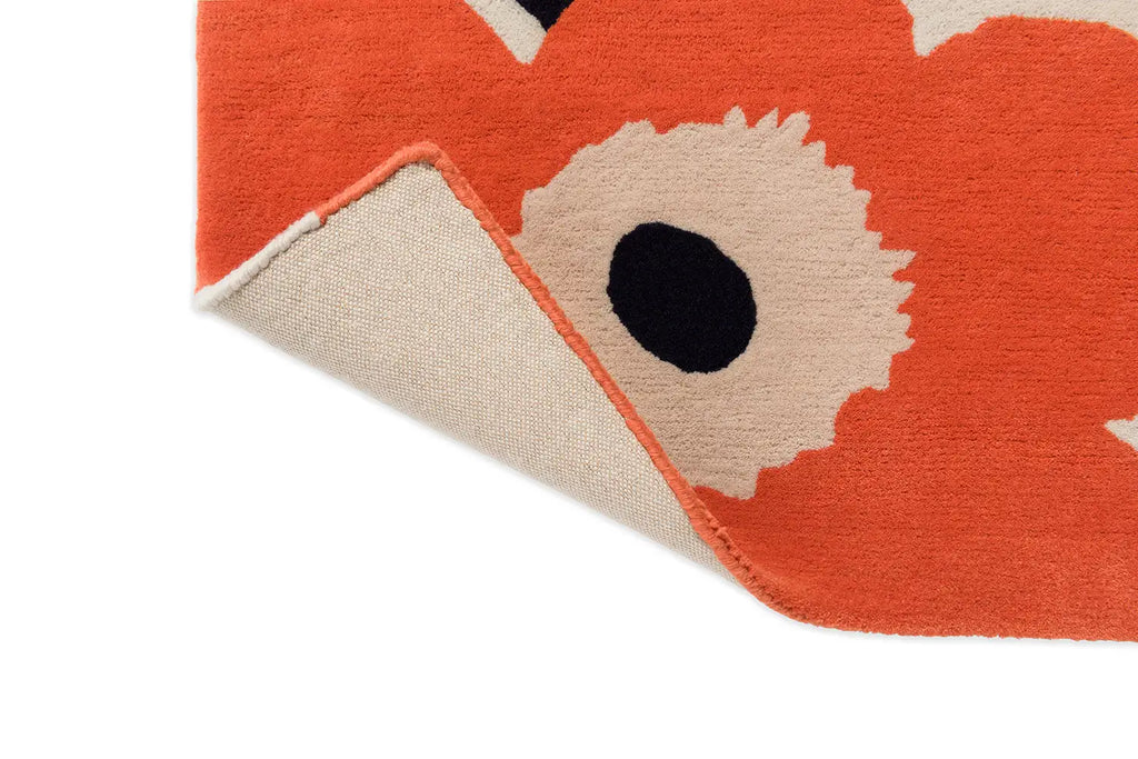 Corner close up of the The Marimekko Unikko wool floor rug in orange-red showing corner folded up to reveal base