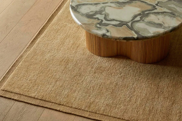 100% wool rug in a warm ochre colour with a contrast frame detail, seen under a coffee table