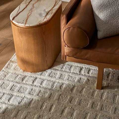 A creamy white wool-blend floor rug featuring an abstract horizontal pattern , seen under a couch leg and coffee table