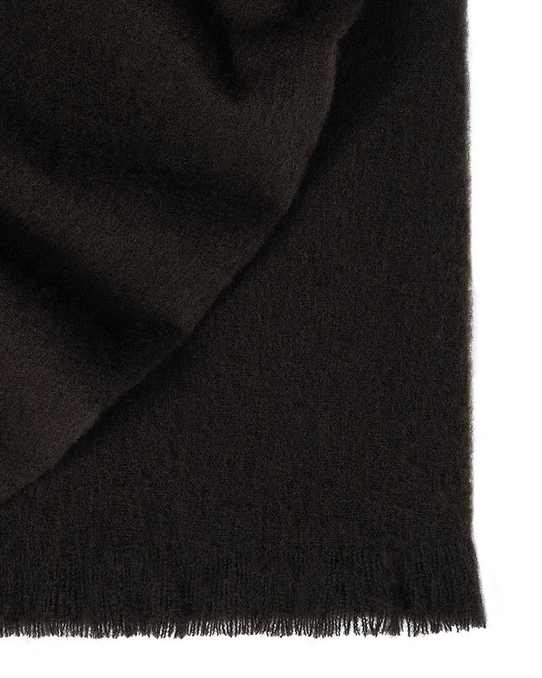 A folded wool blend throw blanket in a dark rich chocolate brown with fringed edging. 
