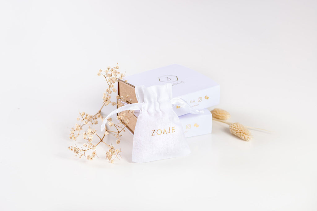 A Zoaje brand white and gold jewellery bag and gift box. 