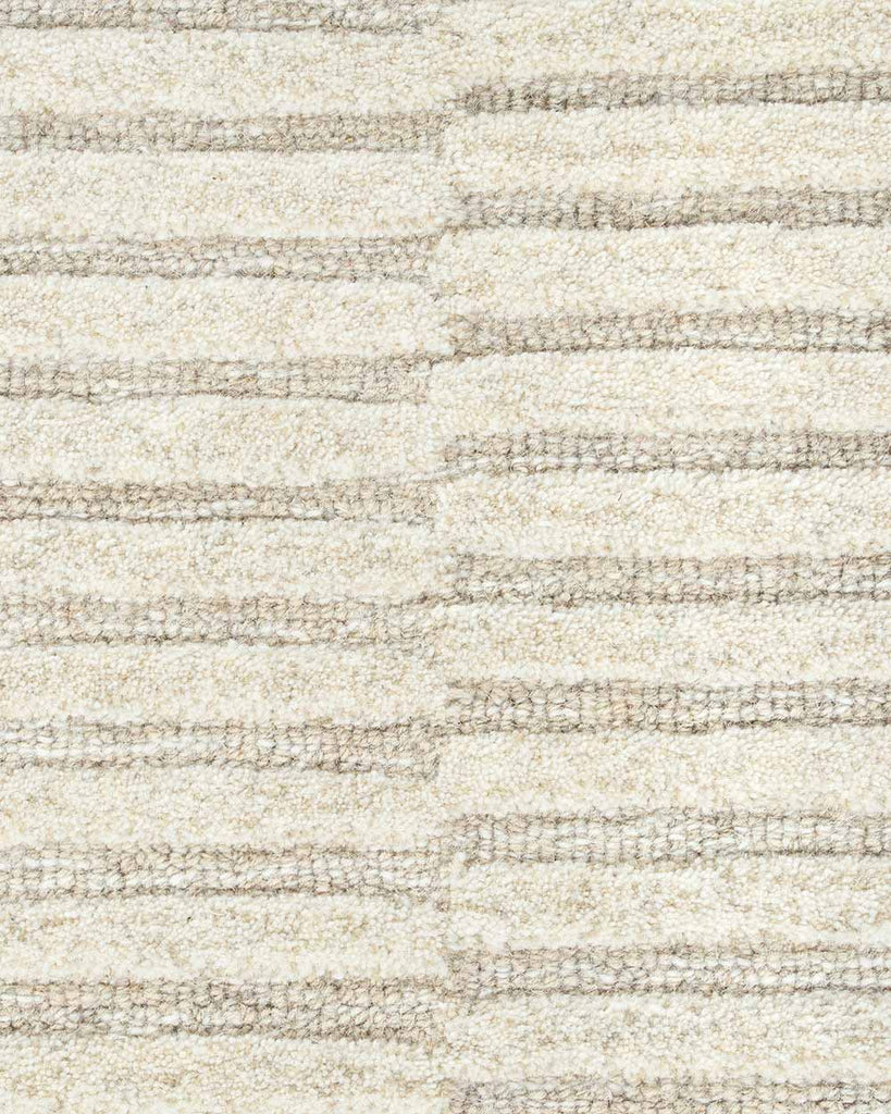A close up image of the weave of this handtufted rug, made with cut and looped pile, in a sophisticated cream colour. 