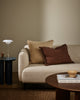 Baya Alden linen cotton blend cushion in Oat, styled on a sofa with a brown fringed lumbar cushion