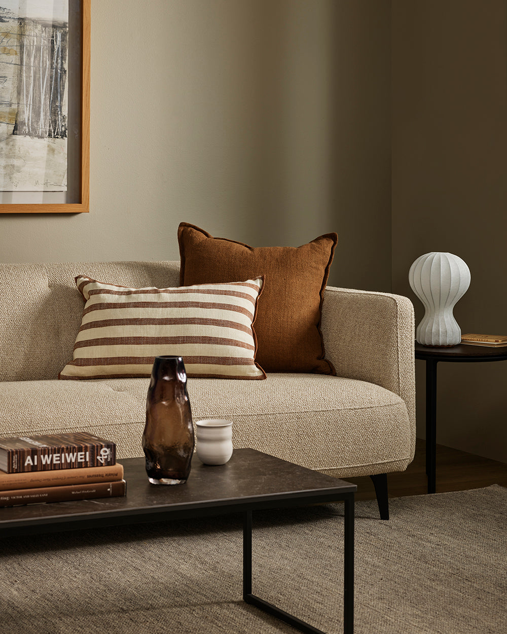 Baya Calden cotton lumbar cushion in Chestnut, styled on a sofa in a moss-green living room