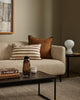 Baya Calden cotton lumbar cushion in Chestnut, styled on a sofa in a moss-green living room