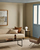 Baya Calden cotton lumbar cushion in Chestnut, styled on a sofa near a blue-framed door