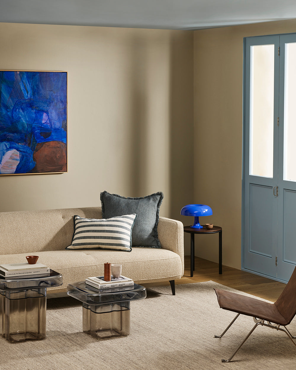Baya Calden cotton lumbar cushion in Cloudburst, styled on a sofa near a blue-framed door
