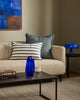 Baya Calden cotton lumbar cushion in Cloudburst, styled on a sofa with a blue glass vase and books on the coffee table