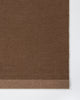Baya Carla NZ wool floor mat in Cocoa, close view of the woven texture and the lighter brown end band.
