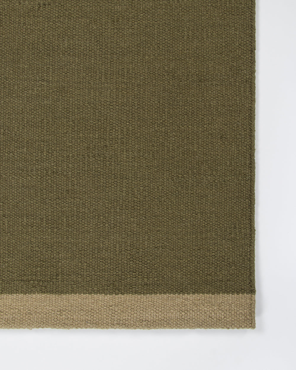 Baya Carla NZ wool floor mat in Military, close view of the woven texture and the pale sand end band.