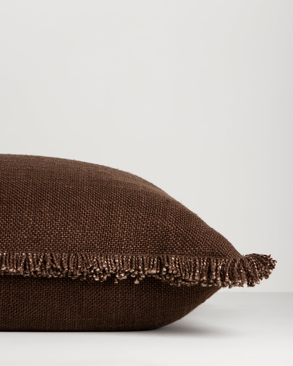 Side profile of the Dover Chocolate cushion showing the fringe along one edge and the cushion's fill