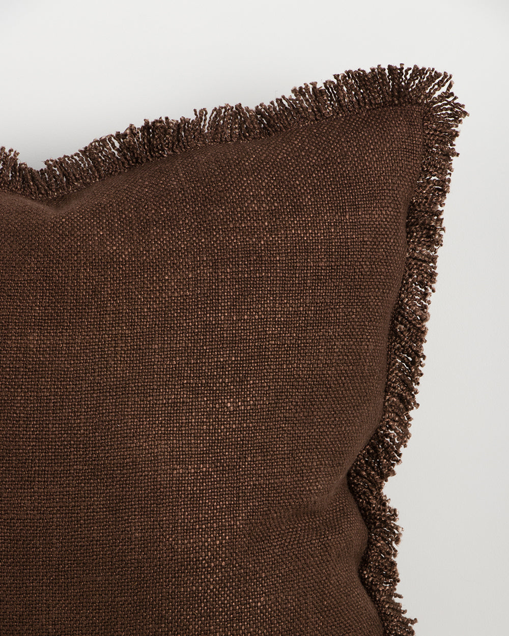 Close detail of the Dover Chocolate cushion's hand-finished fringe trim and woven texture