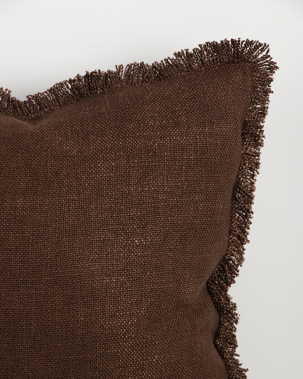 Close detail of the Dover Chocolate cushion's hand-finished fringe trim and woven texture