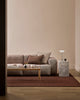Wider view of the Baya Dover Chocolate lumbar cushion styled on a grey sofa in a living room setting